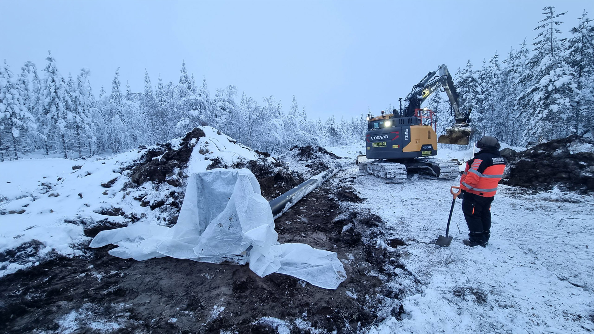 Wintery construction site. A man standing next to a shovel.