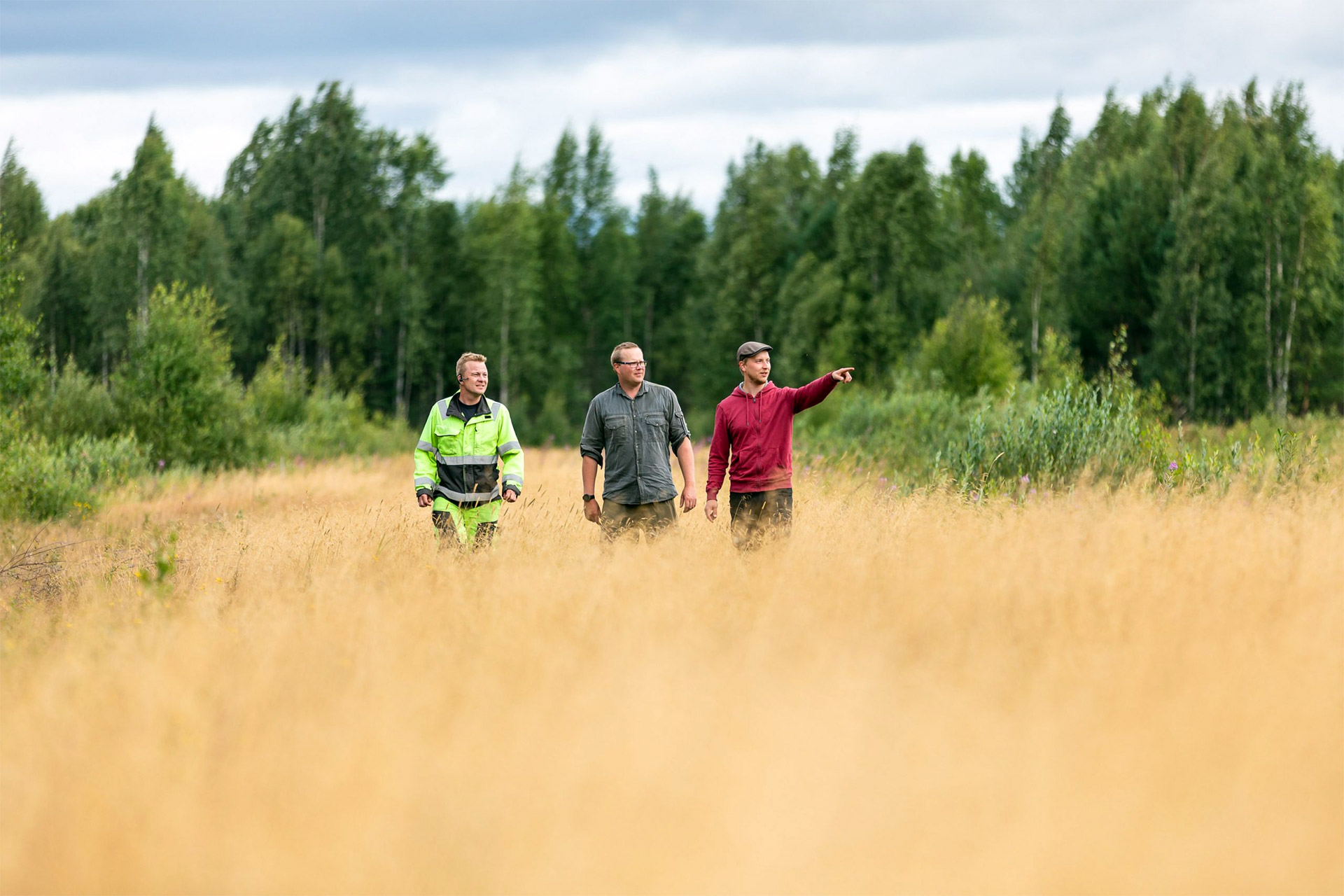 Three persons walking on a field.