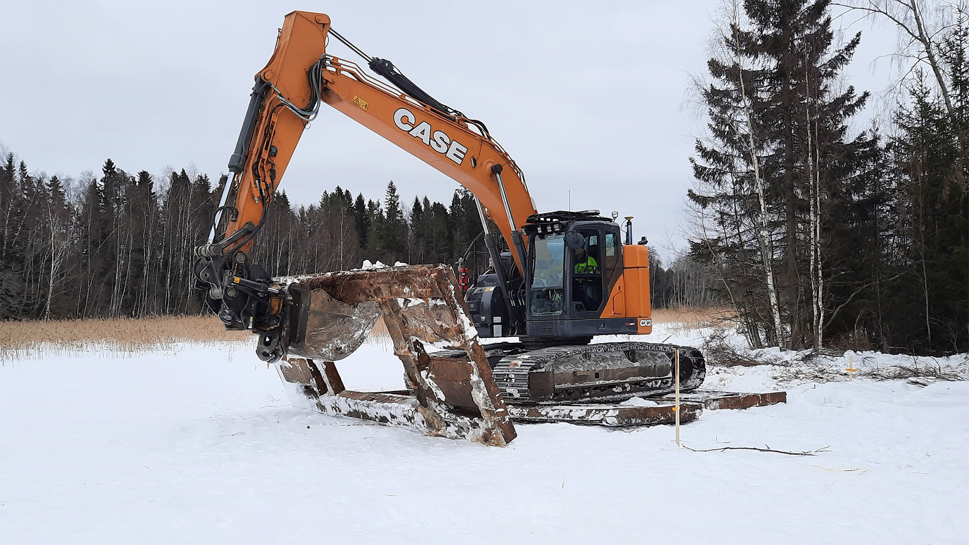 Luminen, avoin maisema, jossa kaivinkone pitelee kaivualustaa.